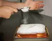 Espolvoreando con azúcar la coca de almendra